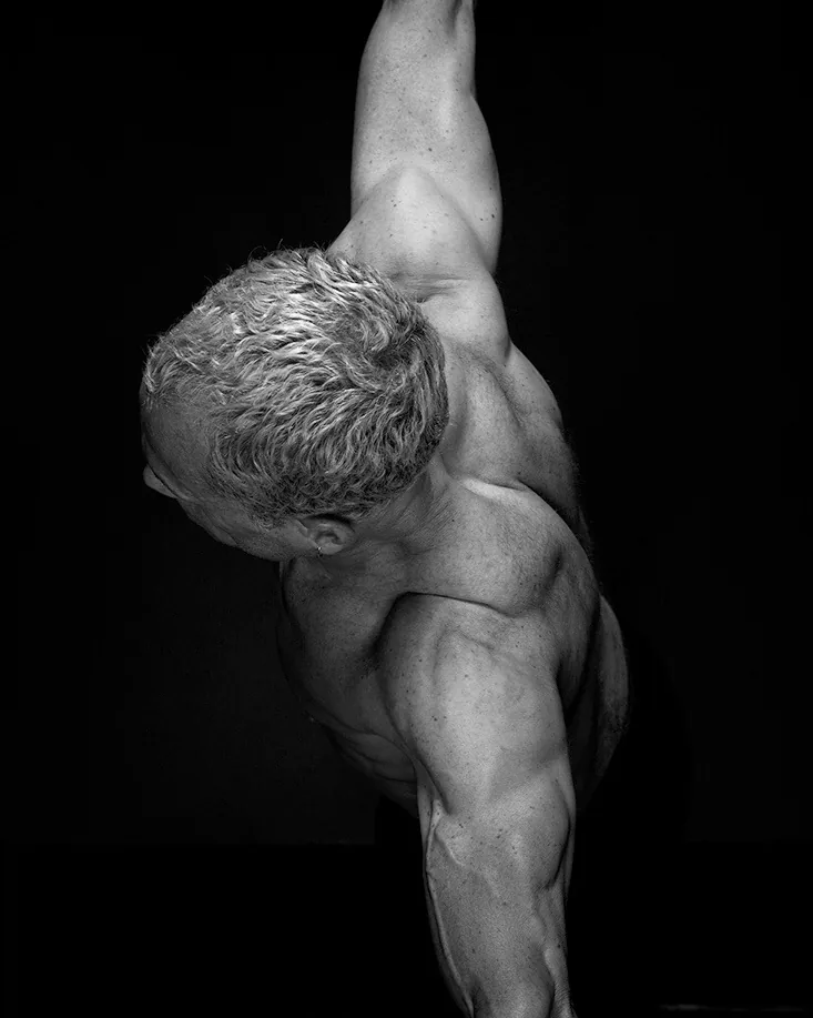 Rick Scott balanced on one leg, black and white studio photograph