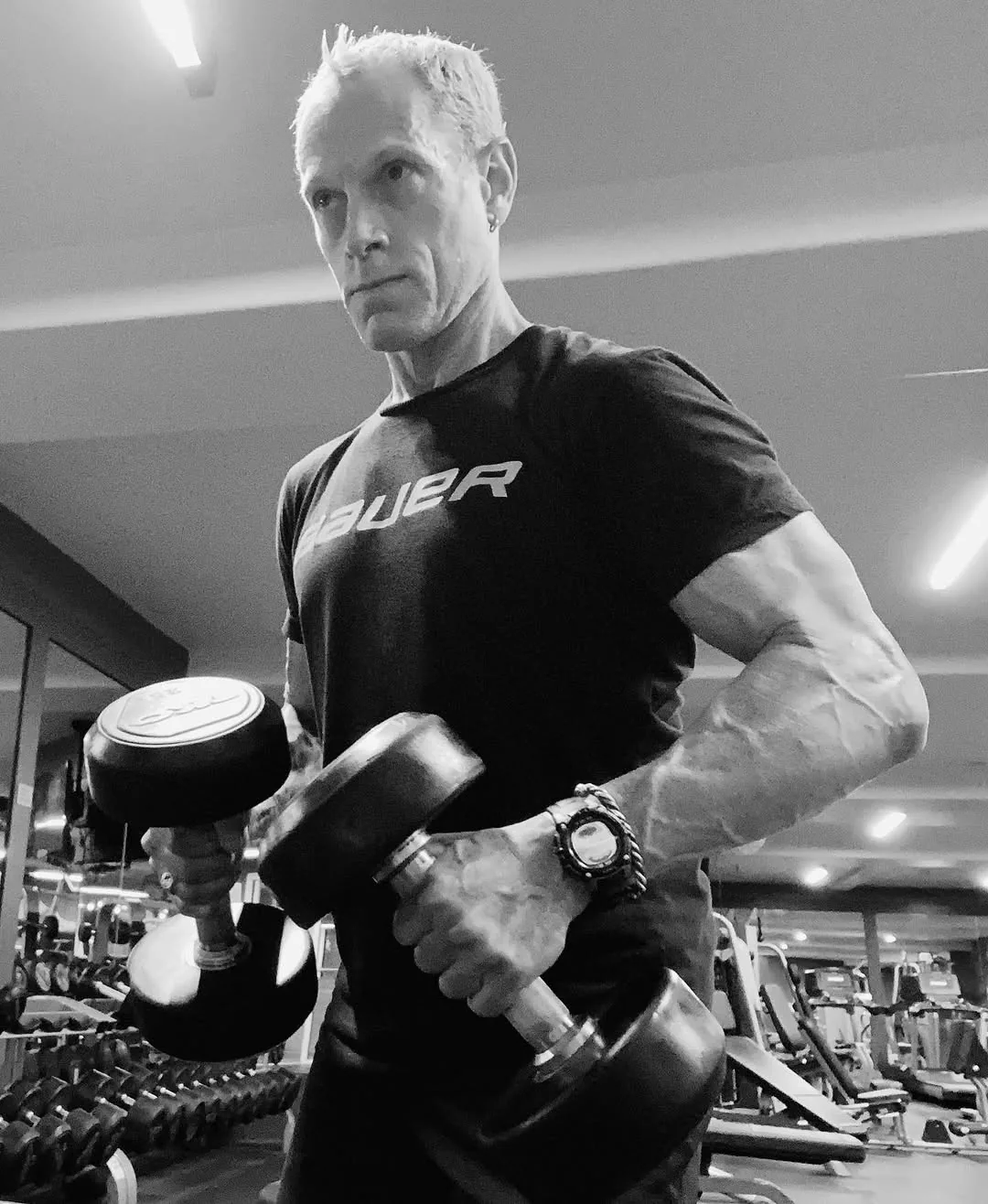 Rick Scott in the gym, a dumbbell in each hand, in a Bauer shirt